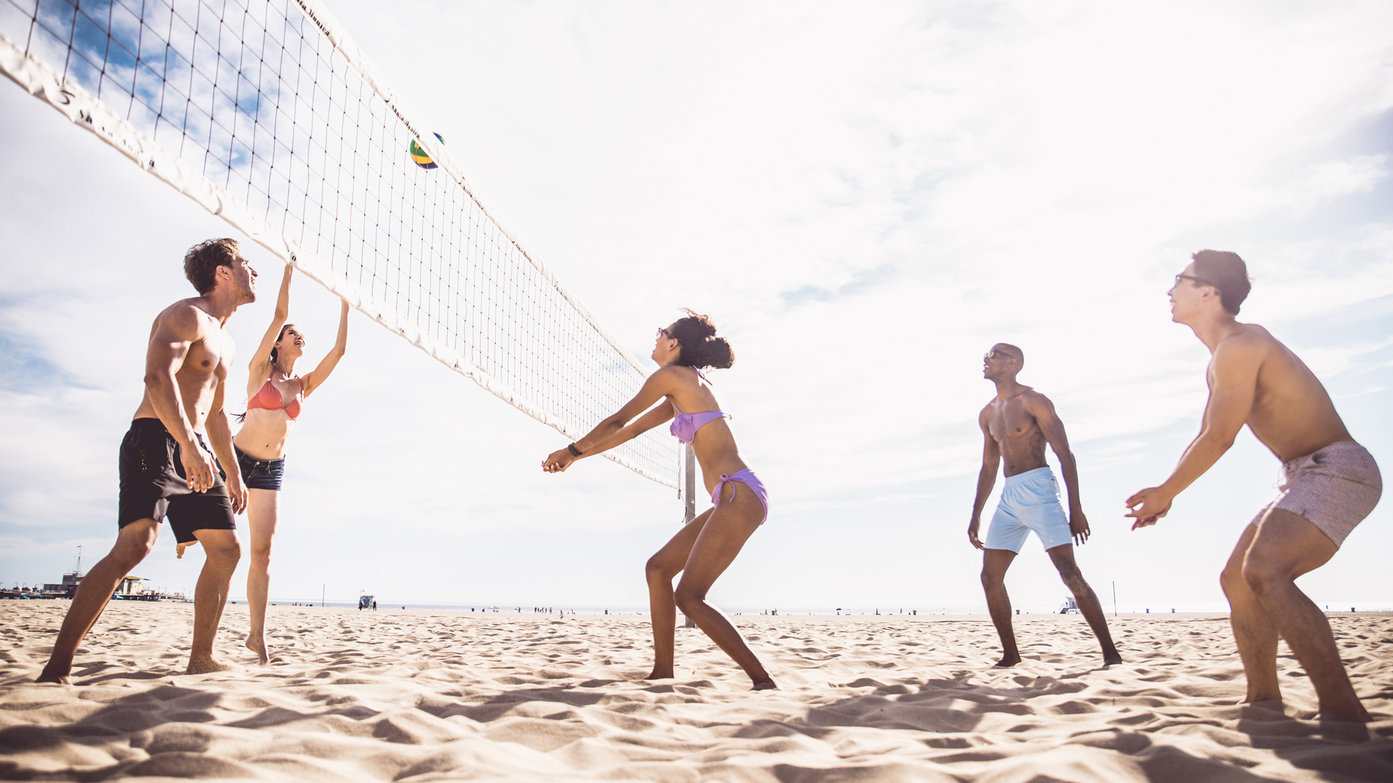 Group of people playing volleyball on sandy beach with large net at Mar Monte Hotel in Santa Barbara, CA