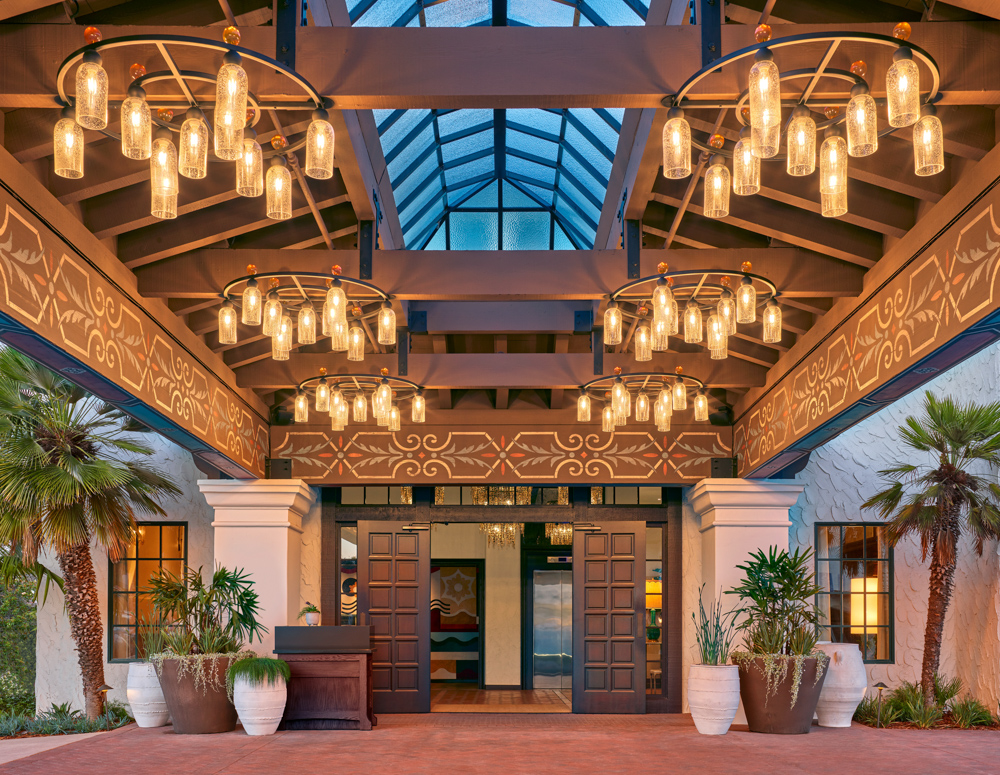 Entrance to Mar Monte Hotel in Santa Barbara, CA with overhead lighting fixtures and a skylight above potted plants
