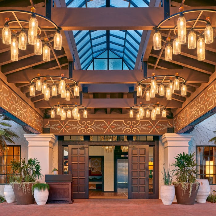 Entry way to Mar Monte Hotel in Santa Barbara, CA with overhead lighting fixtures and a skylight above potted plants
