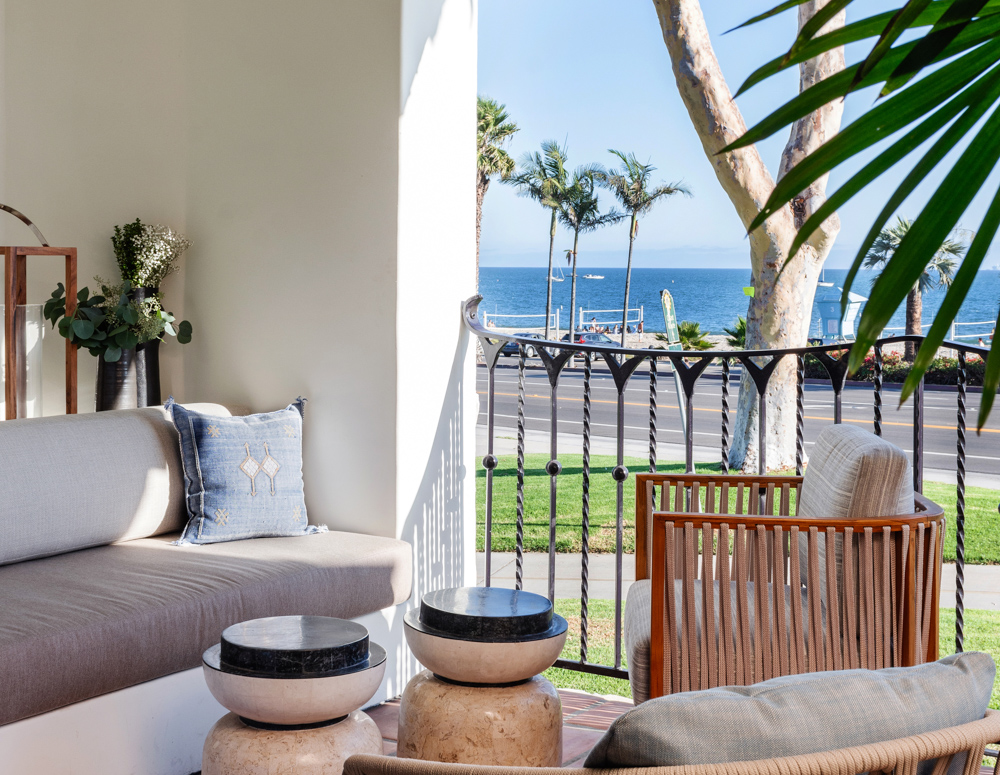 Porch area with brown furniture and colored pillows overlooking ocean, roadway and beach at Mar Monte Hotel in Santa Barbara, CA