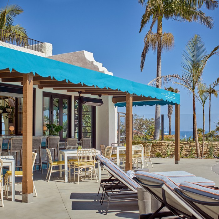 Bar with tables, chairs and poolside loungers in front of palm trees near pool at Mar Monte Hotel in Santa Barbara, CA