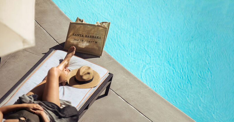 Woman relaxing by the pool with crystal blue water and sun hat
